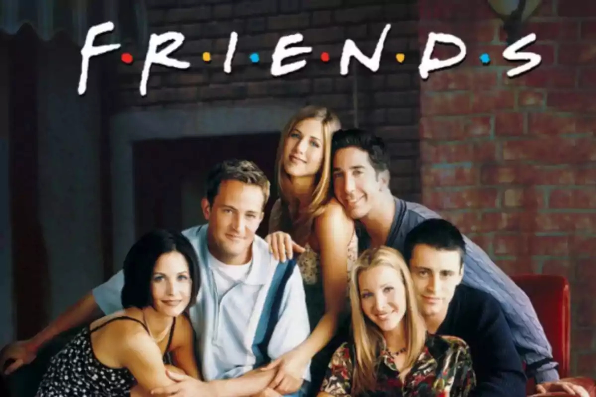 Un grupo de seis personas sonríe frente a una pared de ladrillos con el título "FRIENDS" en la parte superior.