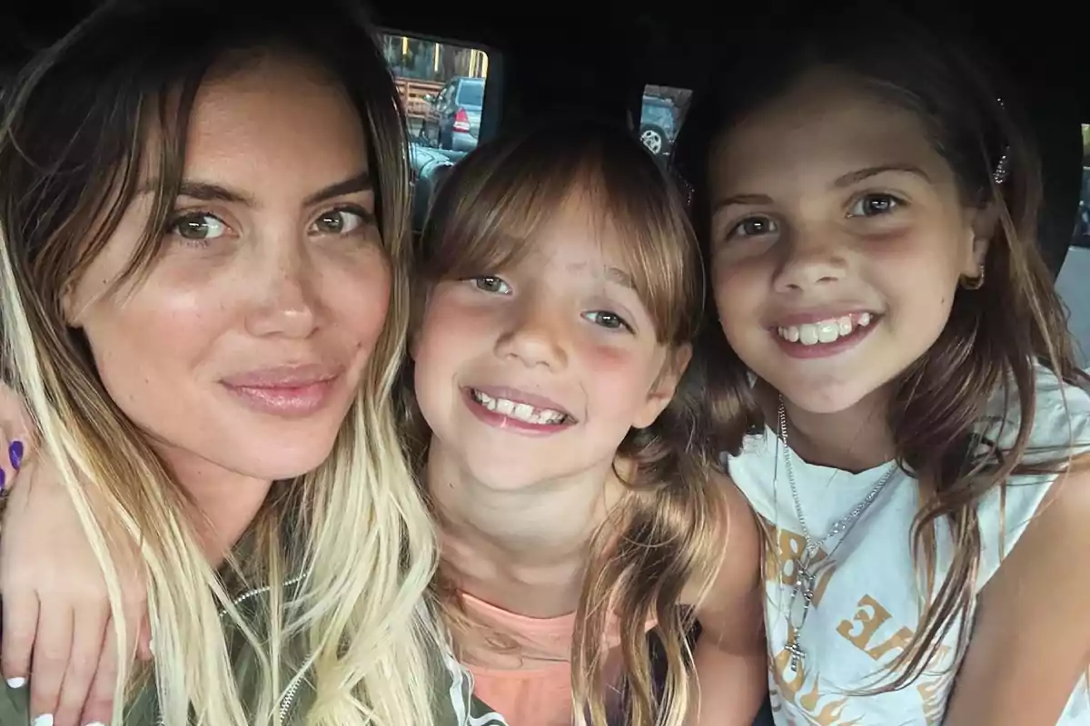 A woman and two girls smile together for a photo.