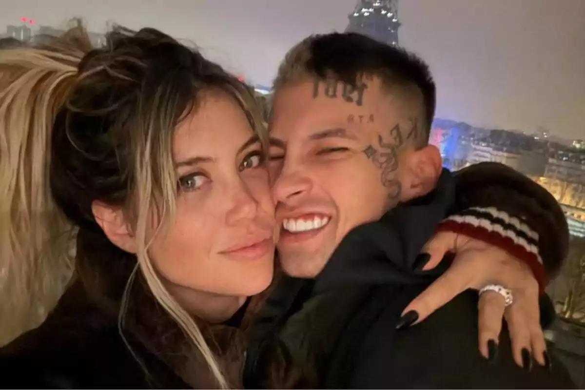 Una pareja sonriente se abraza frente a un paisaje urbano nocturno.