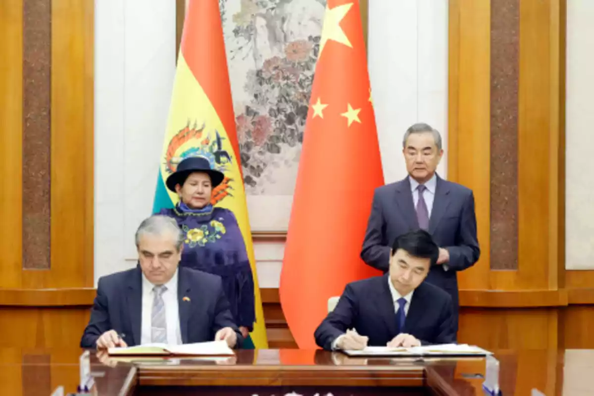 People at a document signing ceremony with the flags of Bolivia and China in the background.