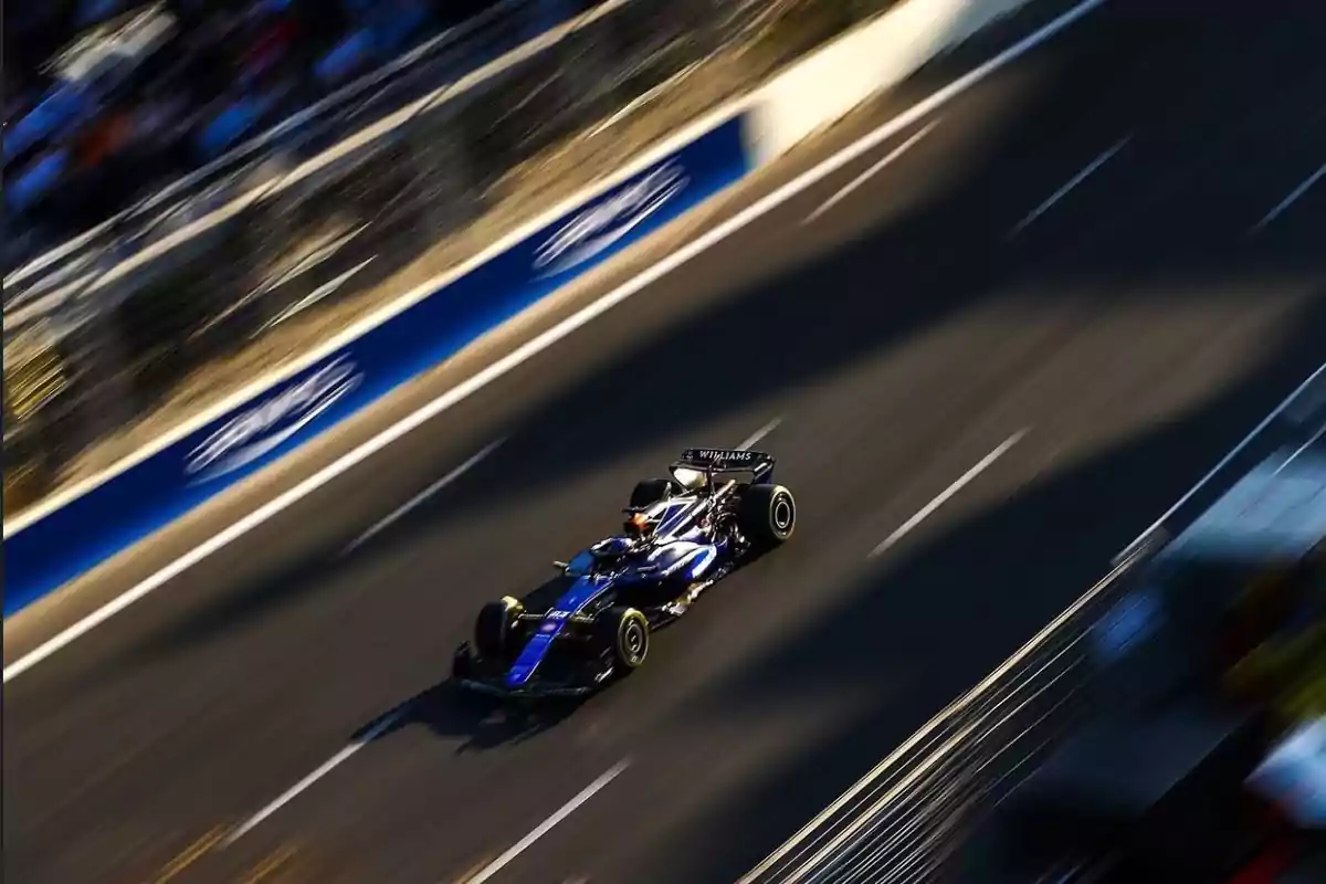 Un coche de carreras azul y negro compitiendo en una pista de carreras.