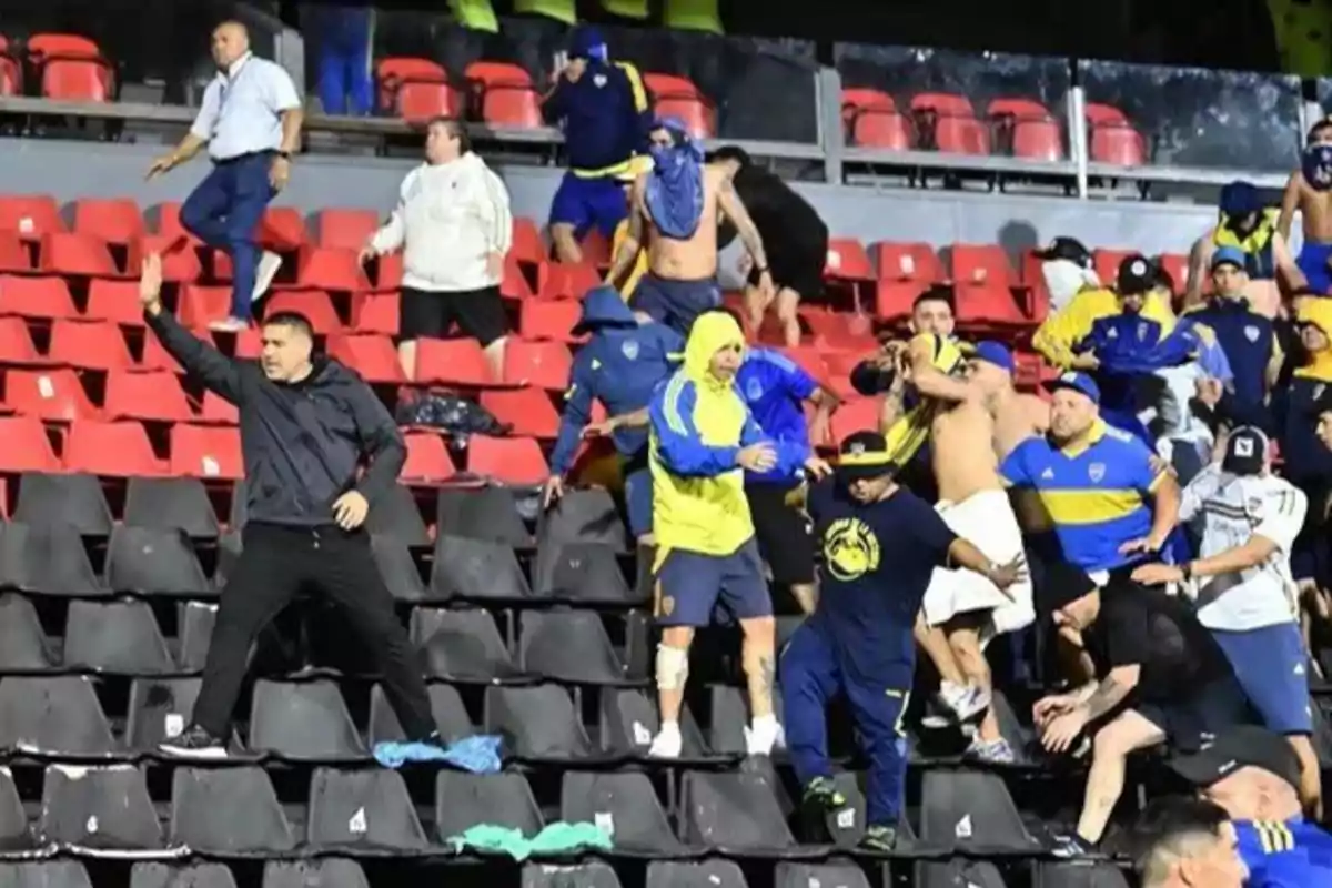 Un grupo de personas con ropa deportiva se encuentra en las gradas de un estadio, algunas de ellas parecen estar en movimiento o agitando los brazos.