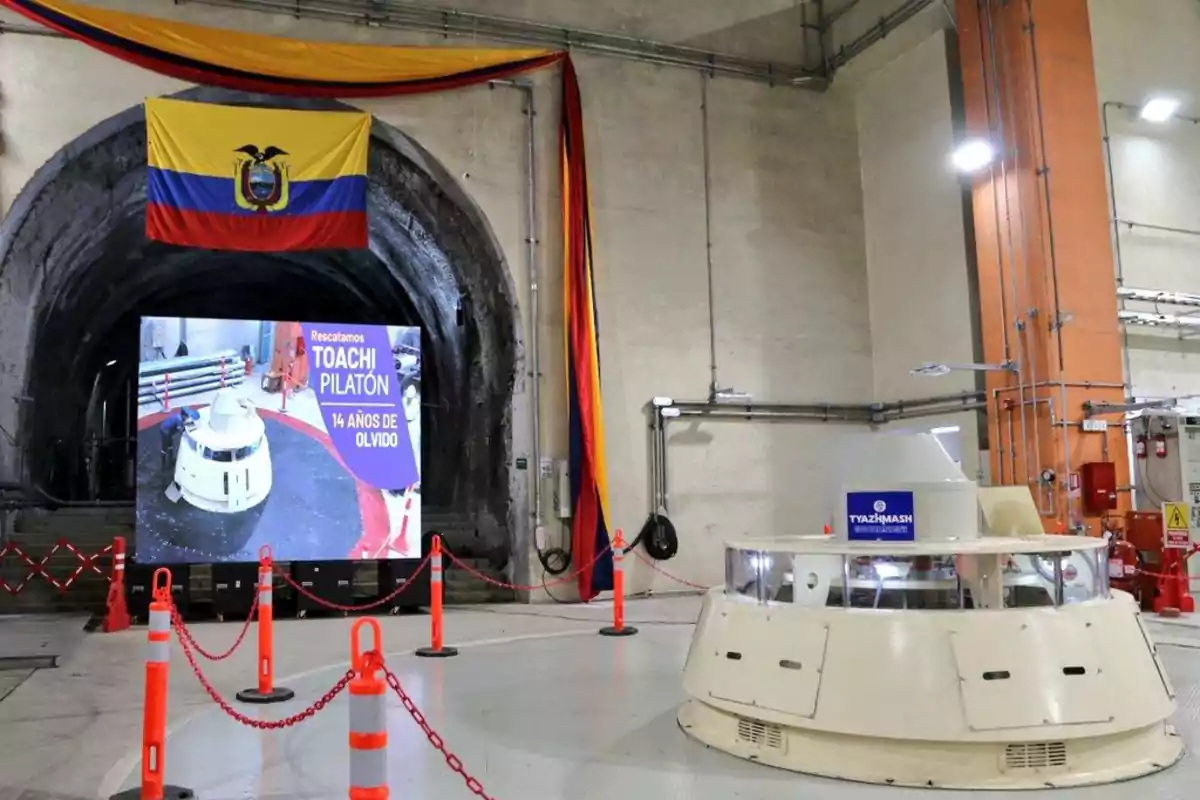 Interior de una planta hidroeléctrica con una bandera de Ecuador colgada en la entrada de un túnel y un cartel que dice 