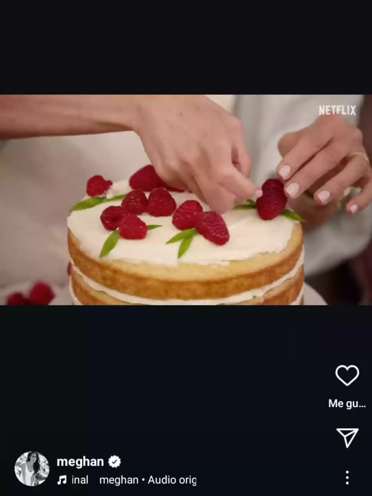 Una persona decorando un pastel con frambuesas y hojas verdes.