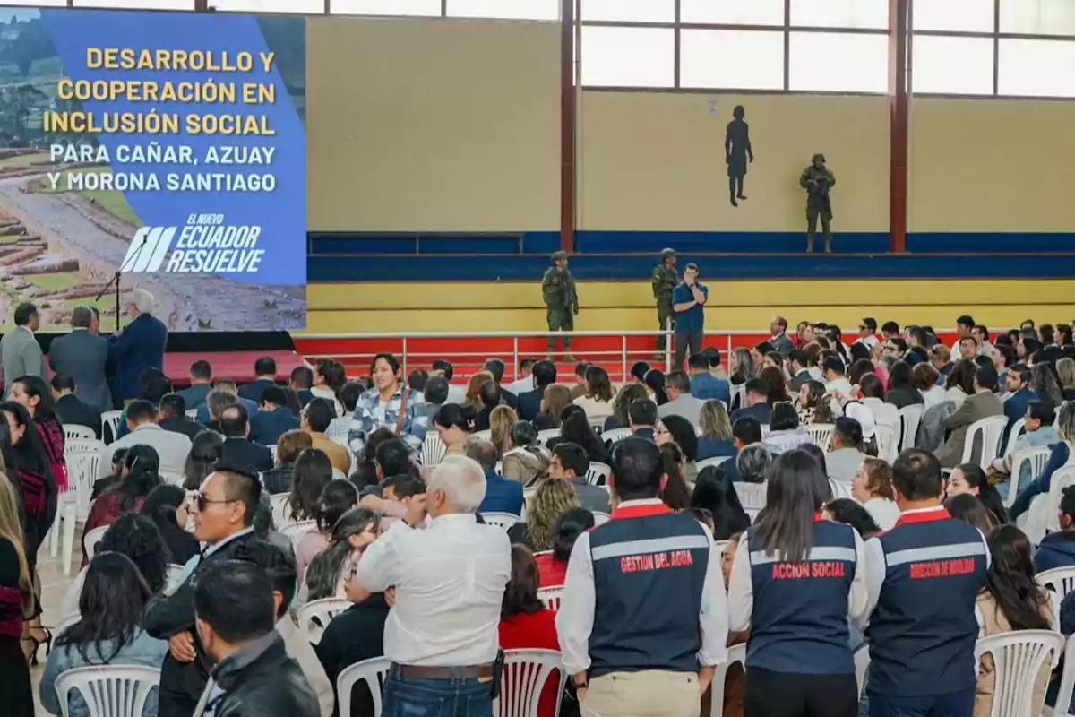 Una conferencia sobre desarrollo y cooperación en inclusión social para Cañar, Azuay y Morona Santiago, con un público numeroso y personal de seguridad presente.