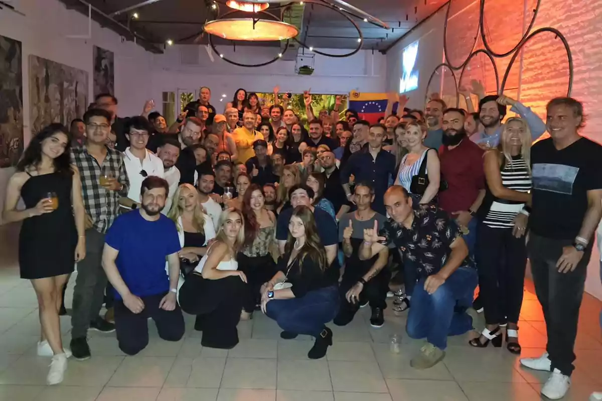 Un grupo grande de personas posando juntas en un ambiente interior con iluminación cálida y decoraciones en las paredes.