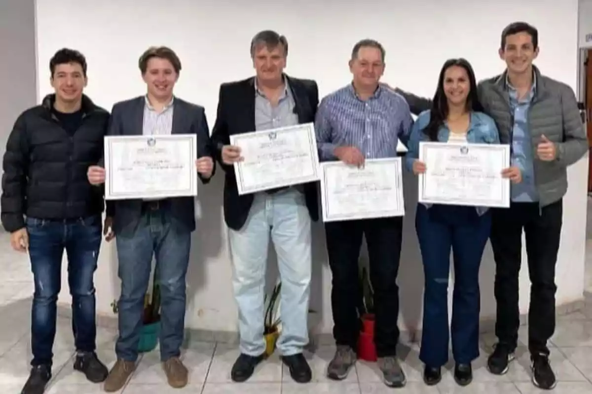 Un grupo de personas posa para una foto, algunas de ellas sostienen certificados en sus manos.