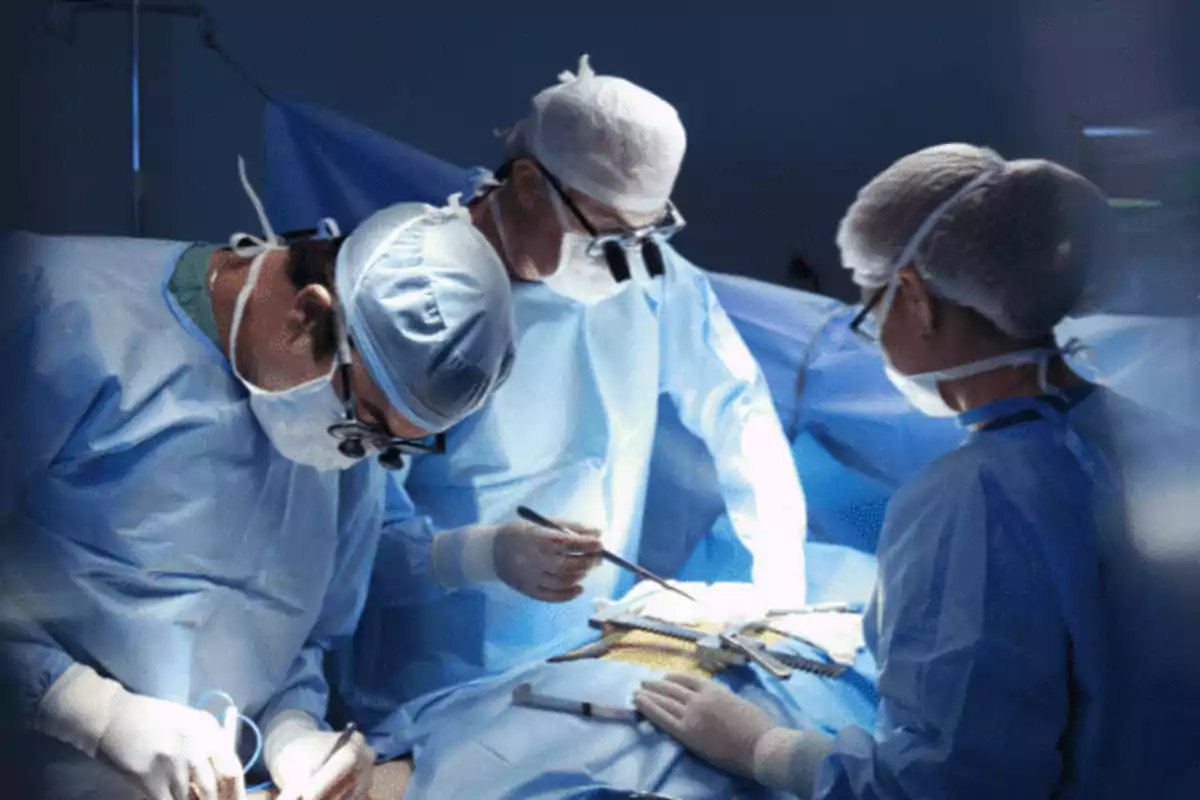 A team of surgeons performs an operation in an operating room, all wearing gowns and masks.